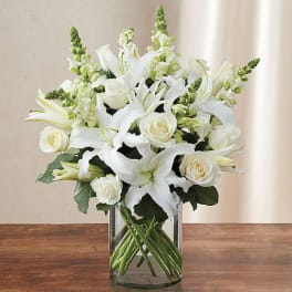 White lilies and roses arranged in a clear glass vase
