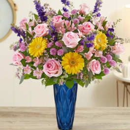 Pink roses and yellow daisies in a blue vase