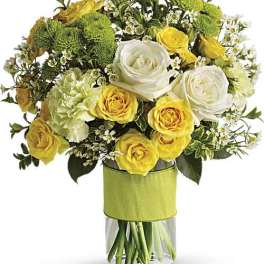 Bouquet of yellow and white roses with green mums in a glass vase