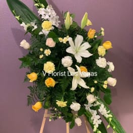 Standing floral spray with white lilies, yellow roses, and white orchids