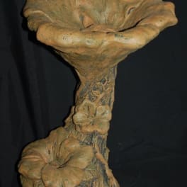 Decorative ceramic birdbath with floral relief and a small bird figure