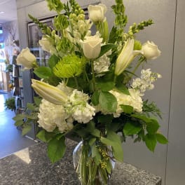 White roses and lilies arranged in a clear glass vase