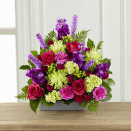 Mixed bouquet of pink, purple, and green flowers in a rectangular vase