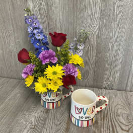 Bouquet of mixed flowers in a decorative mug beside a matching mug