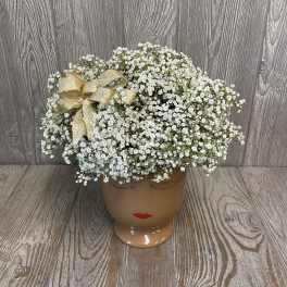 White baby's breath arrangement in a face-shaped ceramic vase with a gold bow