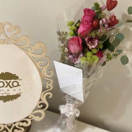 Bouquet of pink roses and green button mums with heart picks in a clear vase