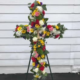Cross-shaped floral tribute on a stand with mixed bright flowers