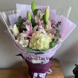 Bouquet of pink lilies and pale hydrangea wrapped in lavender paper
