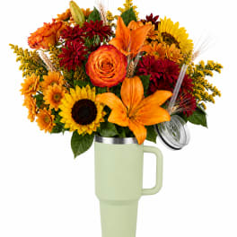 Bouquet of orange, red, and yellow flowers in a handled tumbler vase