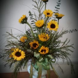 Tall sunflower arrangement in a white vase with green ribbon