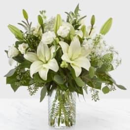 White lilies and roses arranged in a clear glass vase