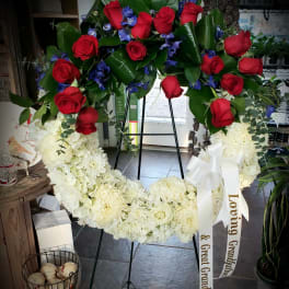 Large standing wreath of red roses and white flowers with a ribbon