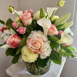 Pink roses and white calla lilies in a clear glass vase