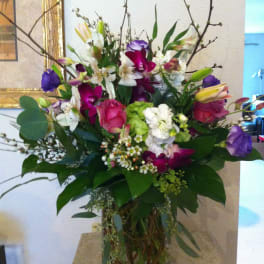 Mixed bouquet of pink, purple, white, and green flowers in a glass vase