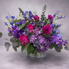 Purple and pink floral arrangement in a clear glass vase