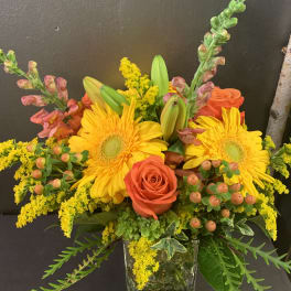 Bright yellow and orange flower arrangement in a clear glass vase