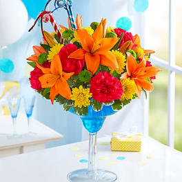Bright mixed flower arrangement in a blue martini glass vase