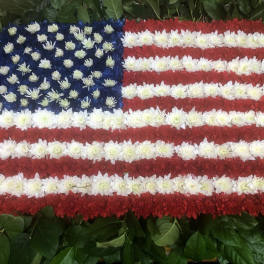 Floral arrangement shaped like the American flag with red, white, and blue flowers