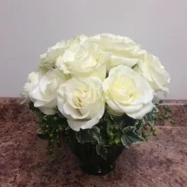 White rose bouquet in a dark vase with variegated greenery