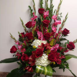 Tall red rose and pink flower arrangement in a white vase