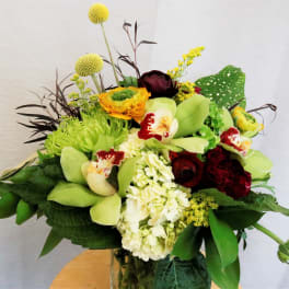 Mixed bouquet with green orchids, white hydrangea, and dark red roses in a vase