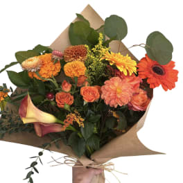 Hand-tied bouquet with orange and yellow flowers wrapped in brown paper