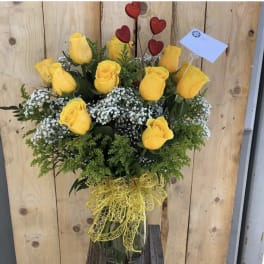 Yellow roses in a clear vase with baby's breath and a red heart pick