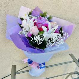 Bouquet of pink and white flowers wrapped in lavender paper
