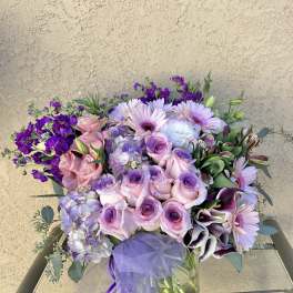 Bouquet of pink and purple flowers in a glass vase with a lavender ribbon