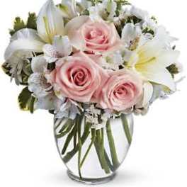 Pink roses and white lilies arranged in a clear glass vase