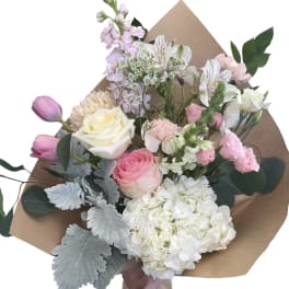 Mixed bouquet of pink and white flowers wrapped in brown paper
