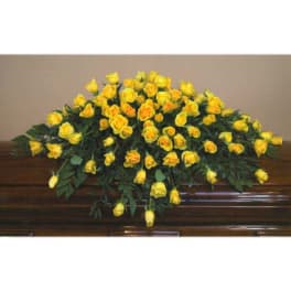 Yellow rose casket spray on a polished wooden casket