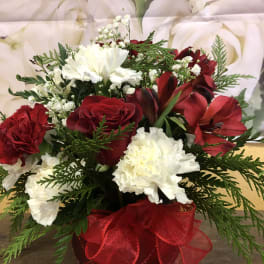 Red and white floral arrangement in a red vase with a ribbon