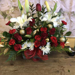 Red roses and white lilies arranged with gold ornaments in a red ribboned basket