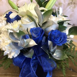 Blue and white floral arrangement with roses, lilies, and carnations in a vase