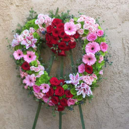 Heart-shaped floral wreath with red and pink roses and pink daisies