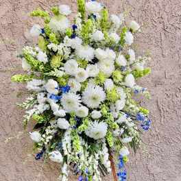 Large white floral standing spray with blue accents on an easel