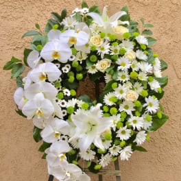 White floral wreath with orchids, daisies, roses, and green accents