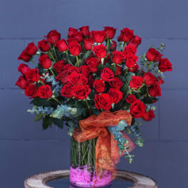 Bouquet of red roses in a glass vase with an orange ribbon