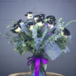 Bouquet of black-and-white roses in a glass vase with purple ribbon