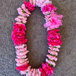 Pink and hot pink carnation lei on a carpeted floor