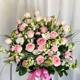 Pink roses and white orchids in a white vase with a pink ribbon