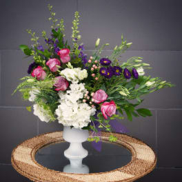 Pink and white floral arrangement in a white pedestal vase