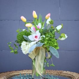 Bouquet of pink-and-yellow tulips with white orchids in a glass vase