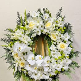 White floral wreath on a wooden easel with orchids and roses