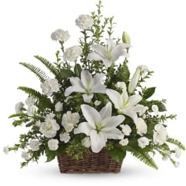 White lilies and carnations arranged in a brown wicker basket