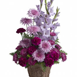Purple floral arrangement in a decorative urn-style pot