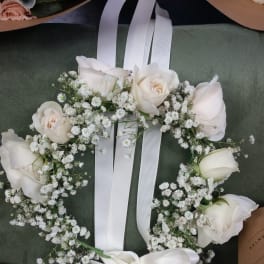 White rose floral wreath with baby's breath and a white ribbon bow