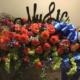 Large floral arrangement with orange roses and blue ribbons