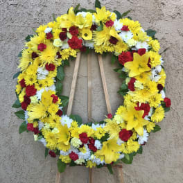 Circular wreath of yellow, red, and white flowers on a wooden easel